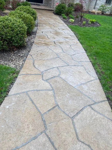 Clean and inviting stone walkway leading to a home after power washing.